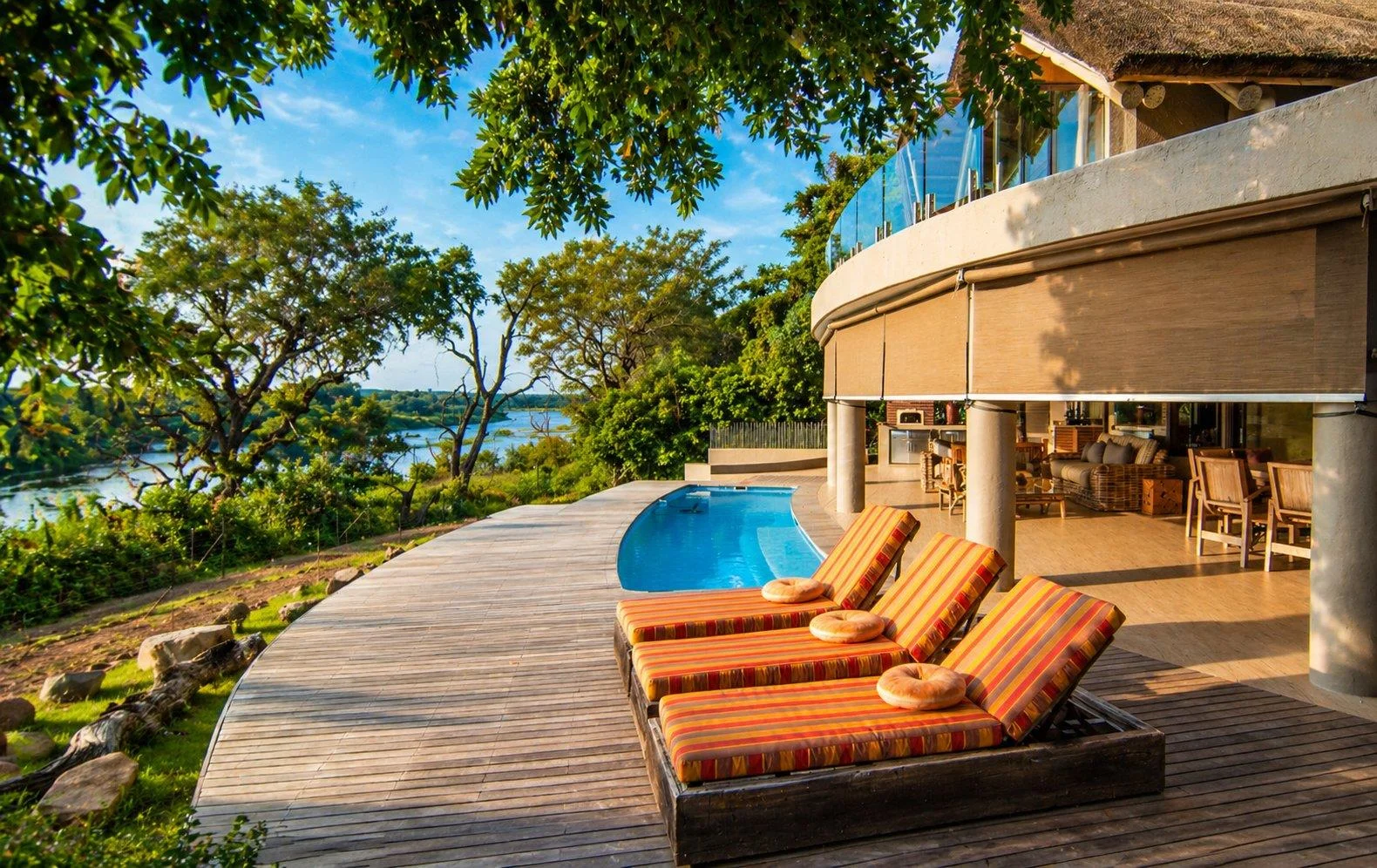 Sun loungers on the timber deck beside the pool, with the river beyond
