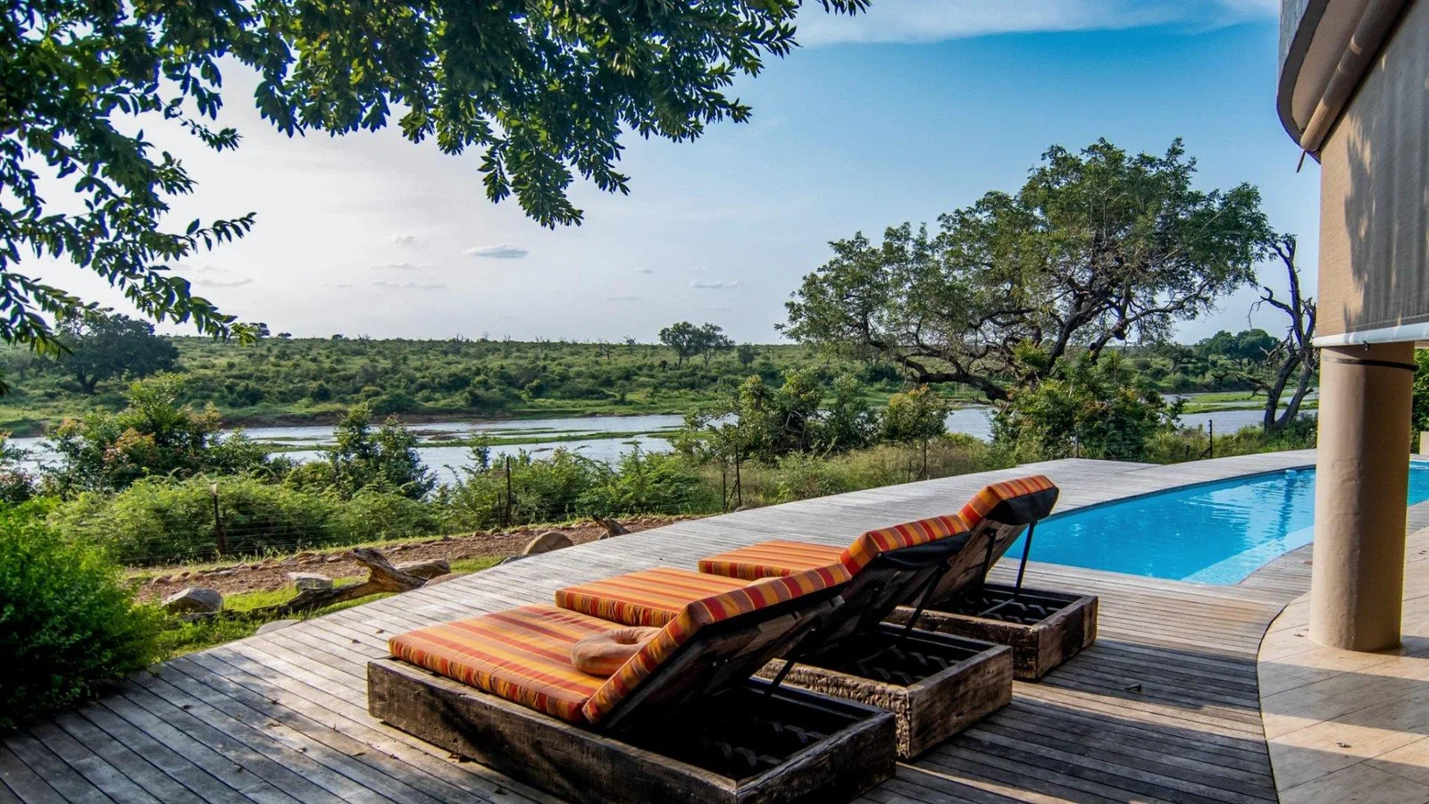 Pool deck with striped loungers and a view across the river and the Kruger