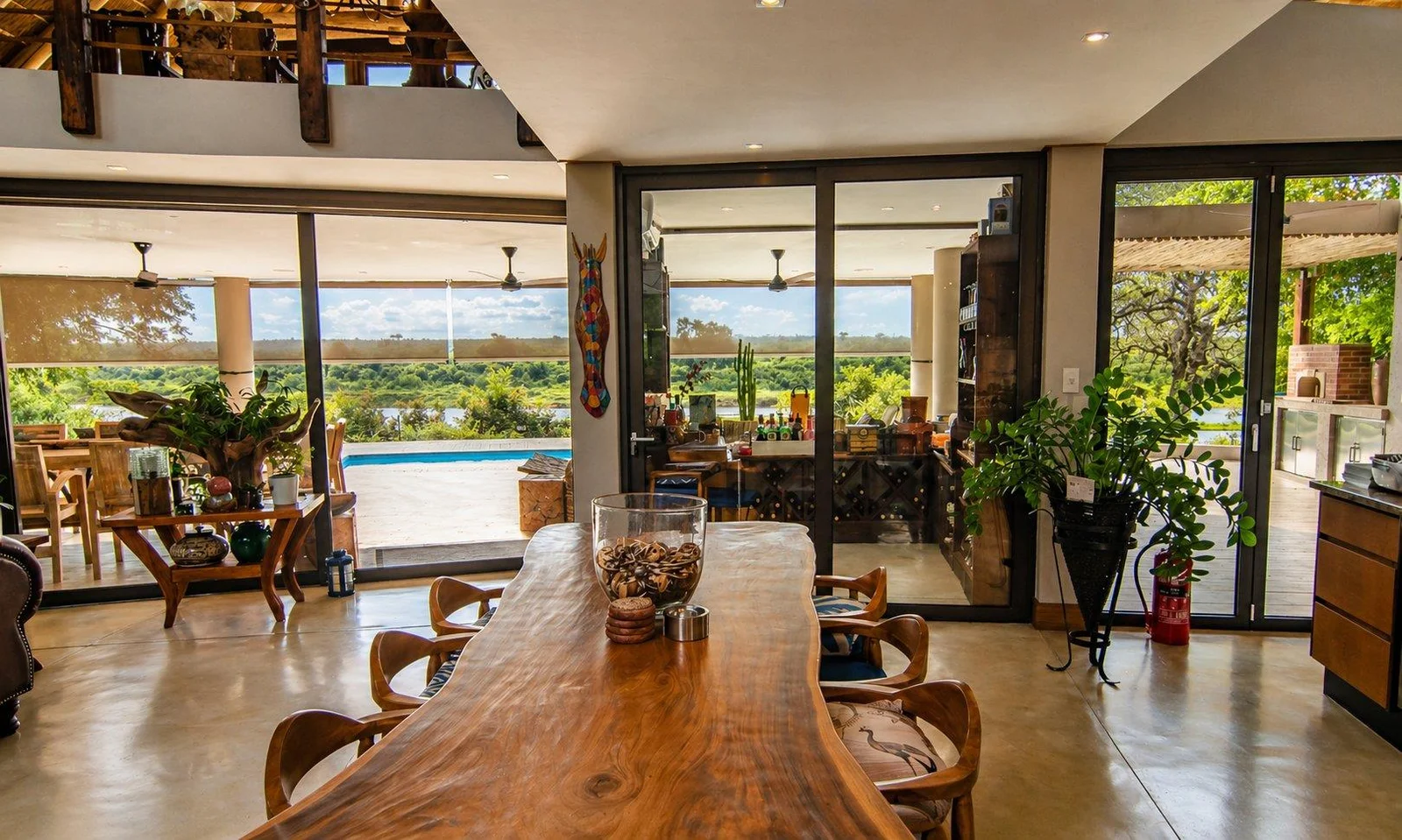 Long timber dining table with glazed doors opening to the pool