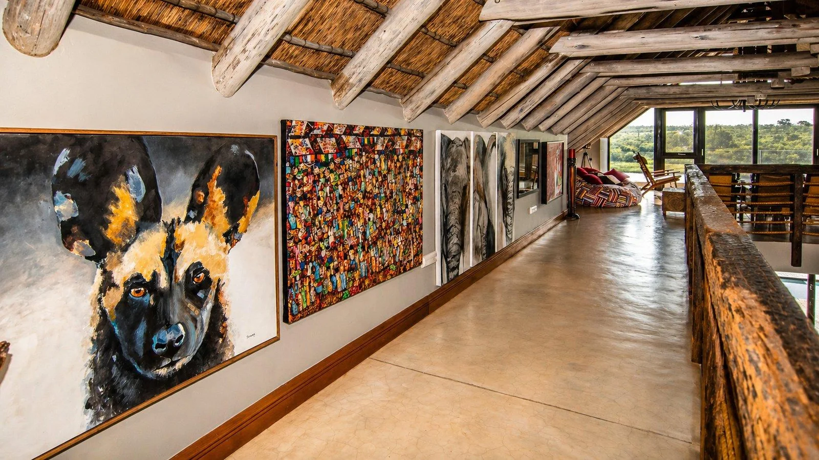 Loft gallery with African wildlife paintings along a timber-trussed passage