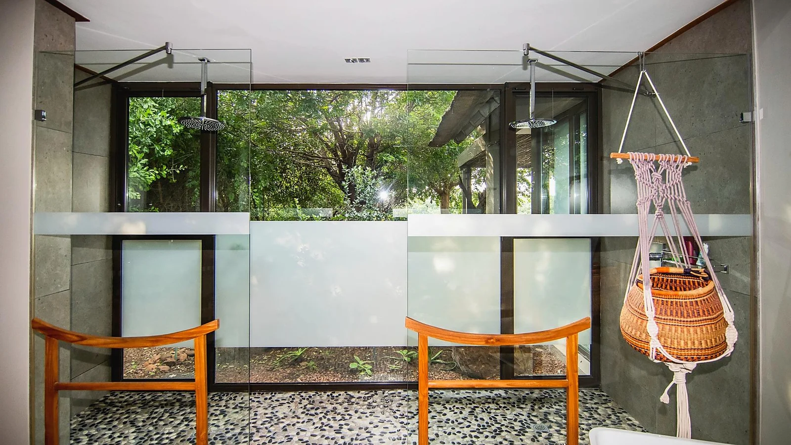 Outdoor shower area with glass screens and a pebble floor