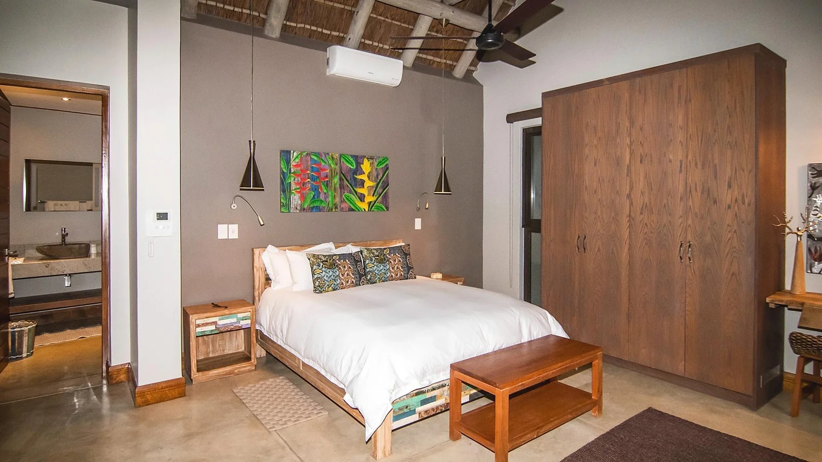Bedroom beneath a thatched ceiling with timber wardrobes