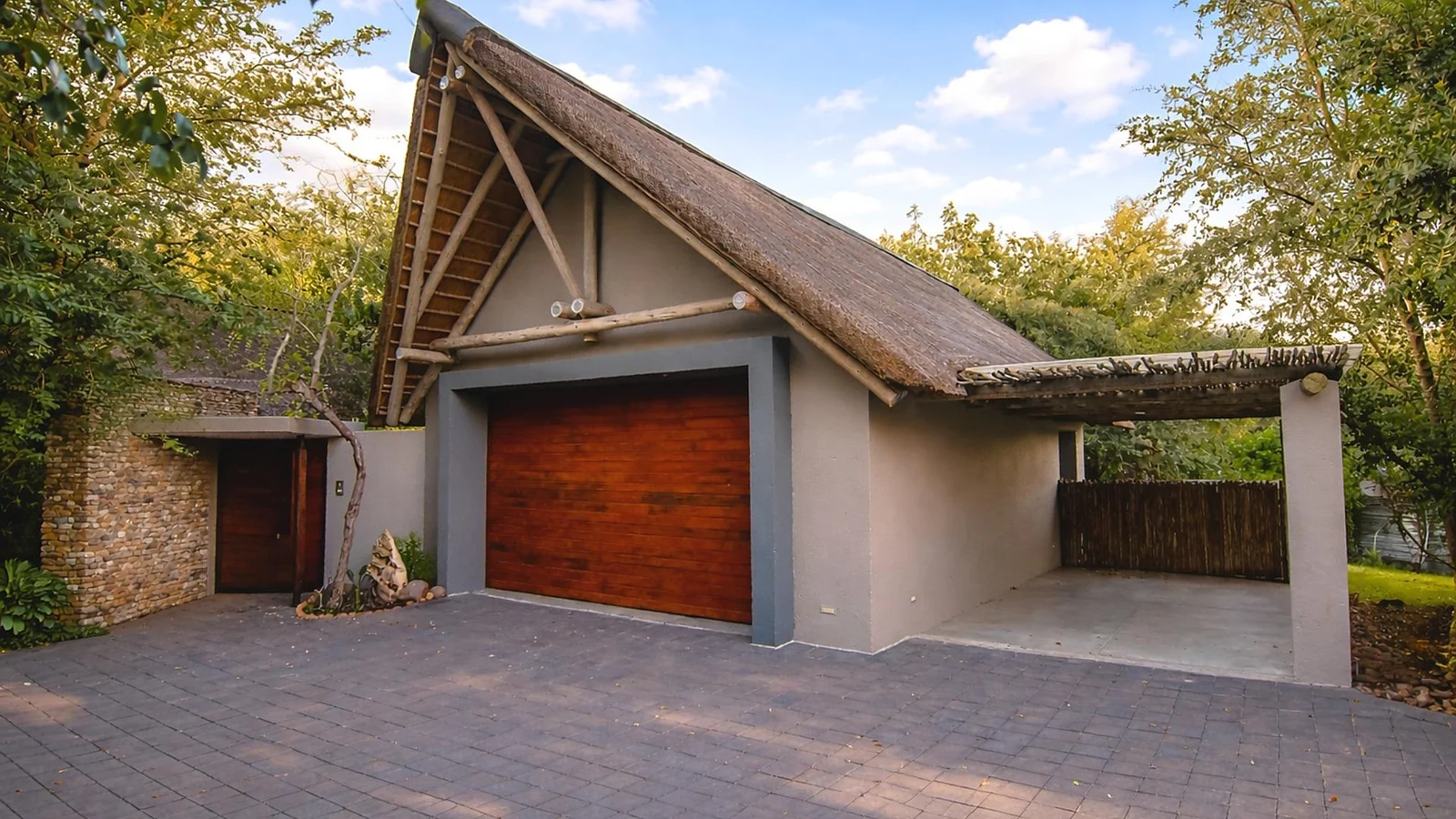 Thatched garage with a timber door and paved forecourt